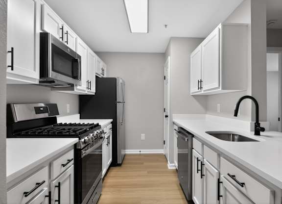 A modern kitchen with white cabinets and black appliances.