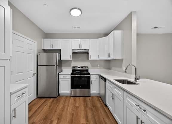 A kitchen with white cabinets and a stainless steel refrigerator.