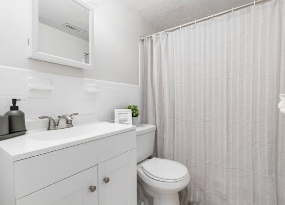 A white bathroom with a toilet, sink, and shower curtain.