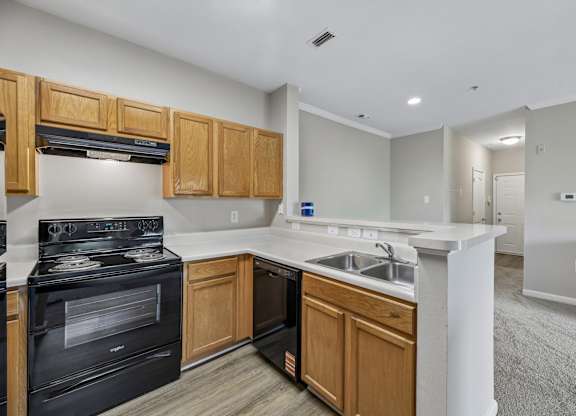 A kitchen with a black stove top oven and wooden cabinets.