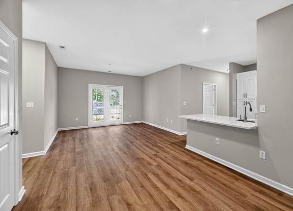A spacious room with wooden flooring and white walls.