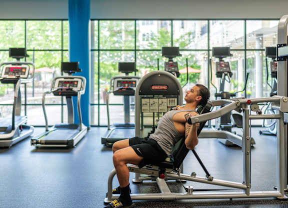 A man is working out on a leg press machine in a gym.