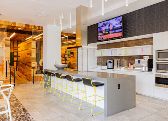 A modern kitchen with a bar area and a television mounted above it.