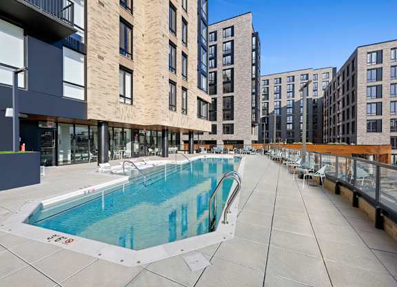 A swimming pool is surrounded by apartment buildings.