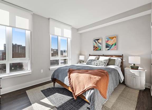 A bedroom with a large bed and a view of the city through the windows.