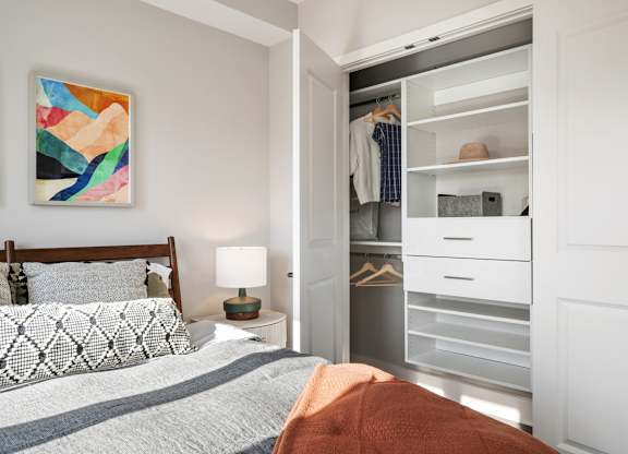 A bedroom with a bed, nightstand, and a painting on the wall.