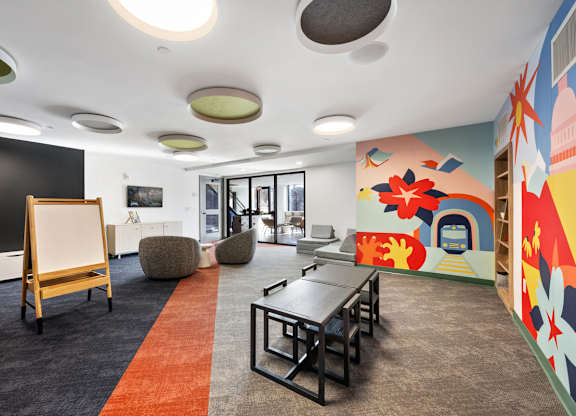 A room with a blackboard, chairs, and a colorful mural on the wall.