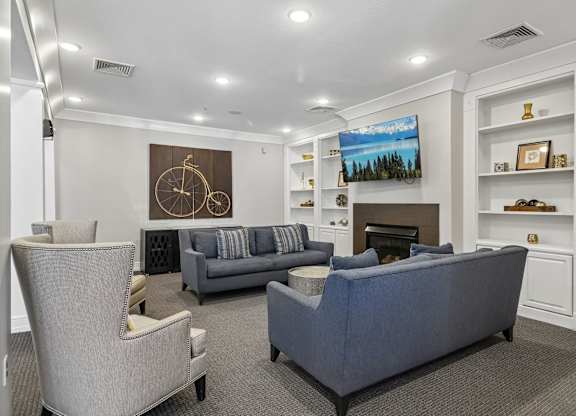 A living room with a grey couch and a painting on the wall.