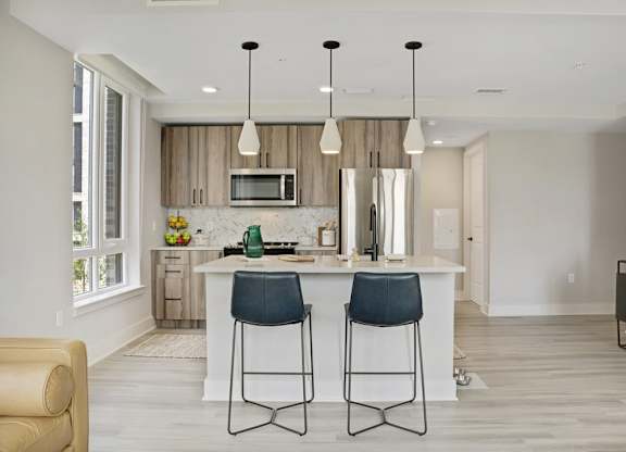 A modern kitchen with a white island and two bar stools.
