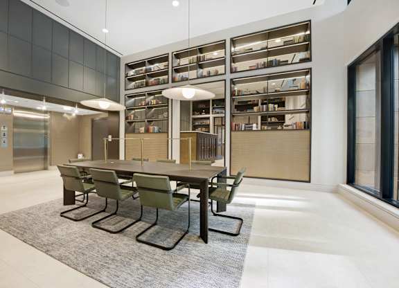 A conference room with a long table and chairs in front of a bookshelf.