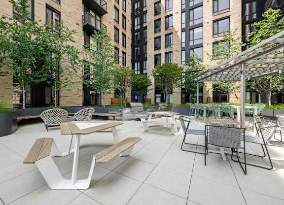 A patio with tables and chairs is surrounded by buildings.