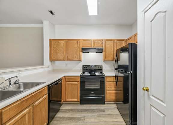 A kitchen with black appliances and wooden cabinets.
