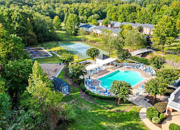 A pool surrounded by trees and a building in the background.