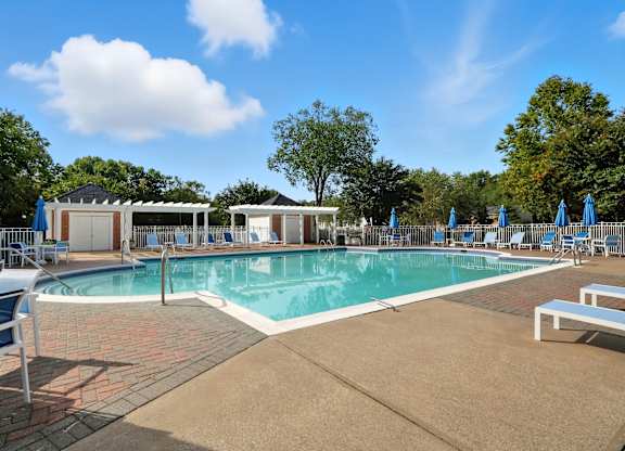 A large outdoor swimming pool surrounded by blue lounge chairs and umbrellas.