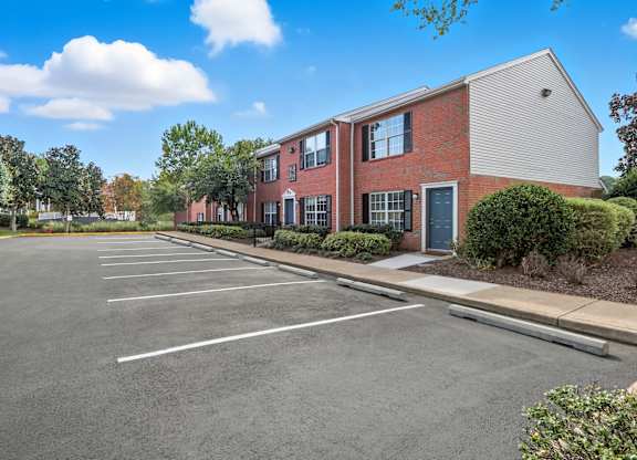 A parking lot in front of a red brick building.