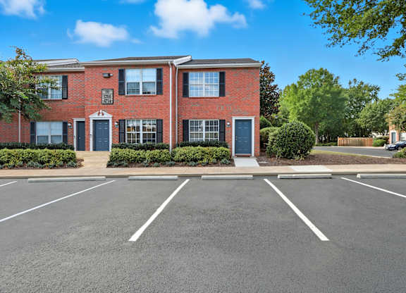 A red brick building with a parking lot in front.
