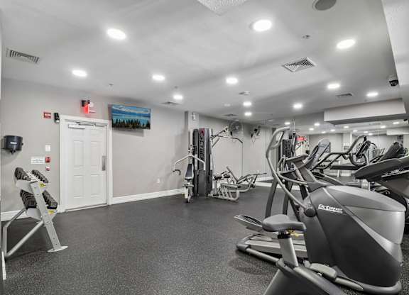 A gym with a variety of exercise equipment including treadmills, stationary bikes, and weight machines.