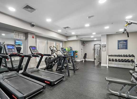 A gym with treadmills, weights, and exercise equipment.