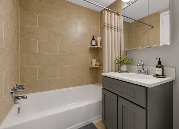 A bathroom with a white bathtub, a sink with a mirror above it, and a toilet.