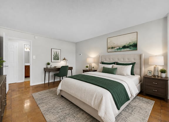 A bedroom with a large bed and a desk with a chair.