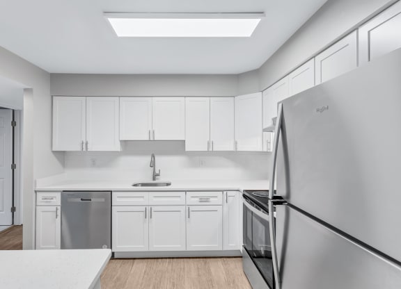 a white kitchen with stainless steel appliances and white cabinets