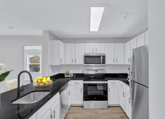 a kitchen with white cabinets and black counter tops