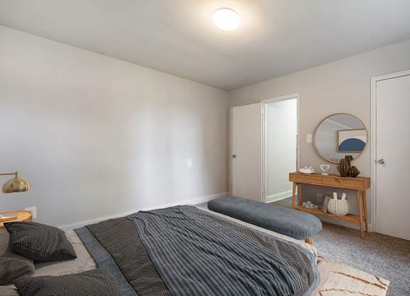 A bedroom with a bed, a nightstand, and a mirror.