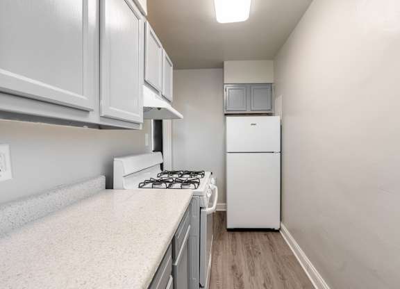 A kitchen with a white fridge, stove and cabinets.