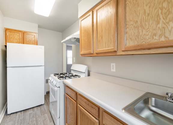 A kitchen with a white fridge, a white stove, and wooden cabinets.
