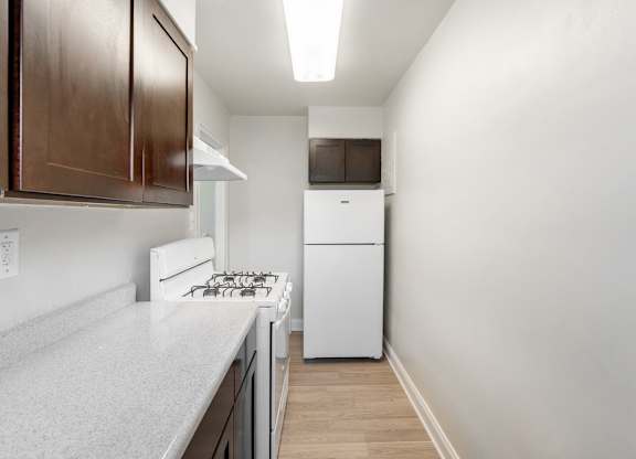 A kitchen with a white stove top oven and a white dishwasher.