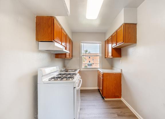 A kitchen with a white stove and wooden cabinets.