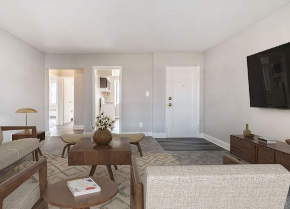 A living room with a couch, coffee table, and a flat screen TV mounted on the wall.