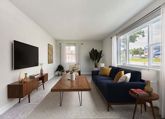 A living room with a blue couch and a television on the wall.