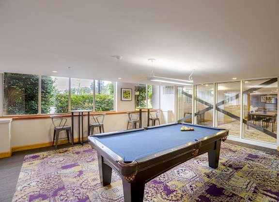 A pool table in a room with a view of the backyard.