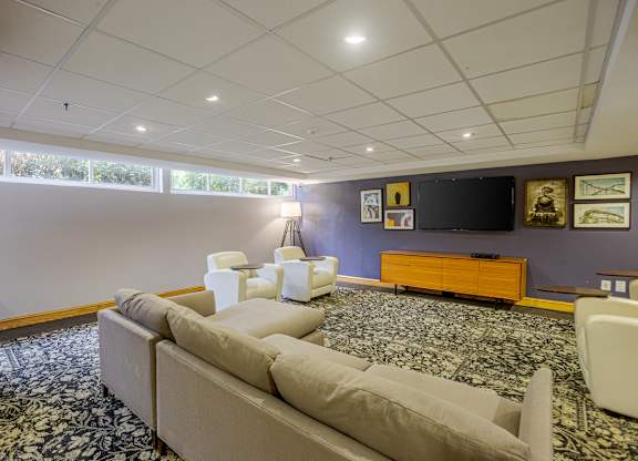 A living room with a couch, chairs, and a television.