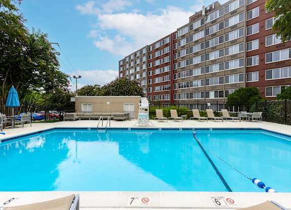 A large swimming pool in front of a red brick building.