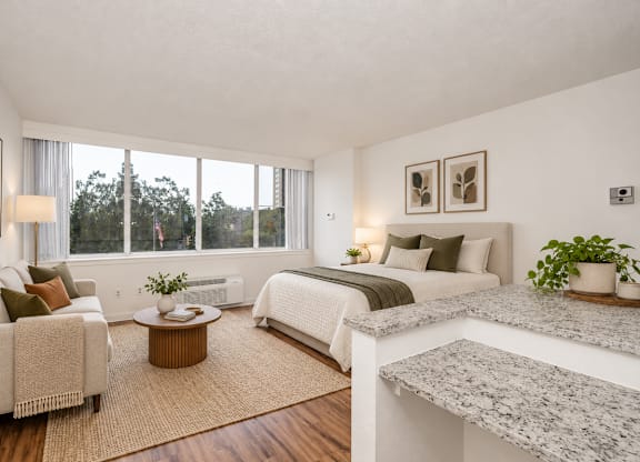 A well-lit bedroom with a large bed, a couch, and a coffee table.