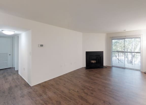 an empty living room with wood floors and a fireplace