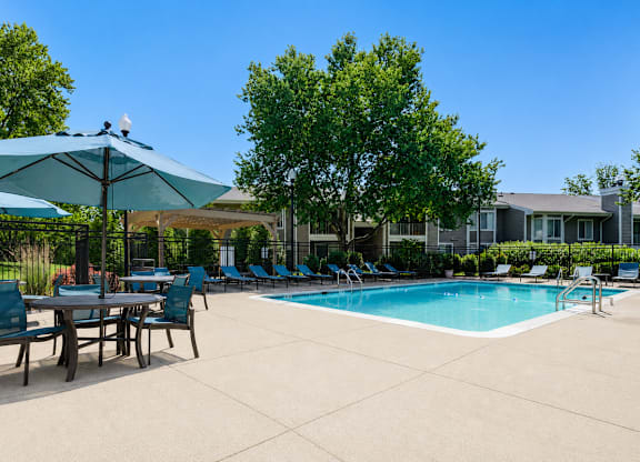A pool area with chairs and umbrellas.