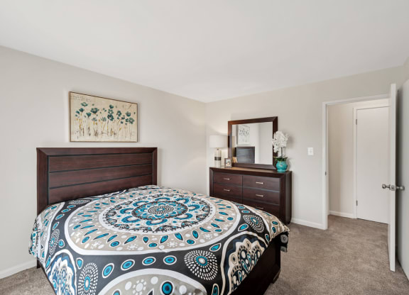 a bedroom with a large bed and a dresser with a mirror