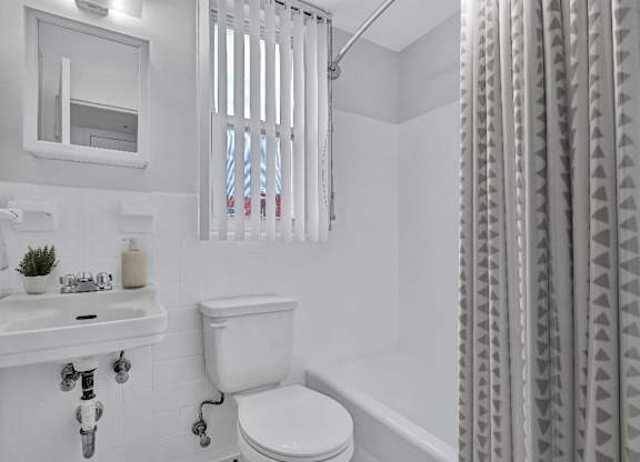 A white bathroom with a toilet, sink, and shower curtain.