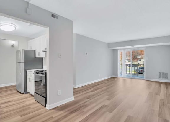 a living room and kitchen with a door to a balcony