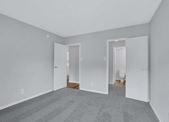 a bedroom with a carpeted floor and a door to a bathroom