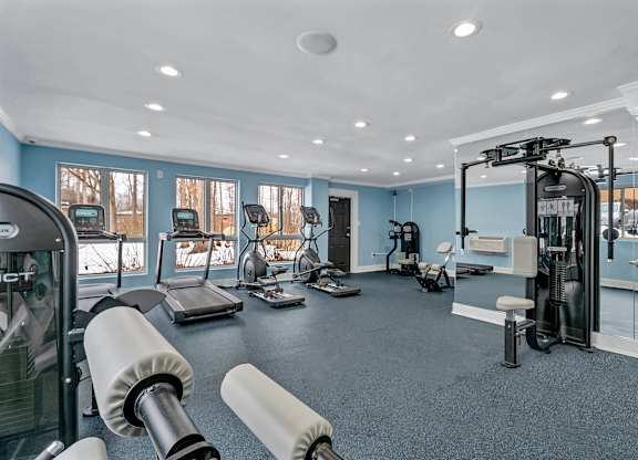 A gym with a variety of equipment including treadmills, weights, and exercise machines.
