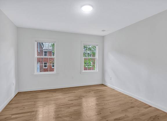 A room with wooden floors and two windows.