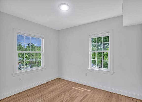 A room with two windows and wooden flooring.