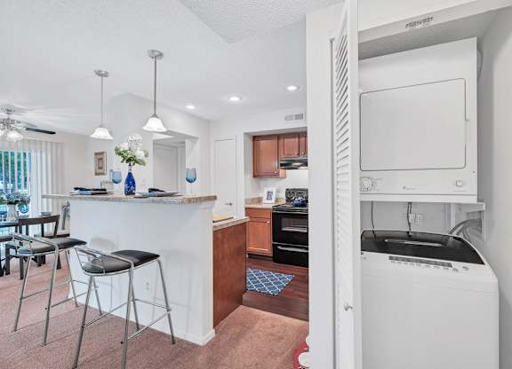 a white kitchen with a bar and a dining room