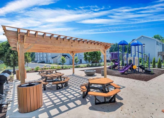 a picnic area with benches and a playground in the background