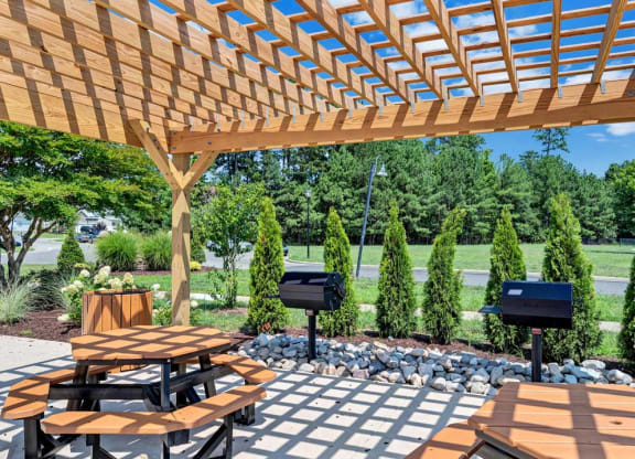 a wooden pergola with a table and benches under it