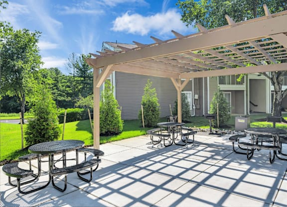 a patio with tables and chairs under a wooden pergola